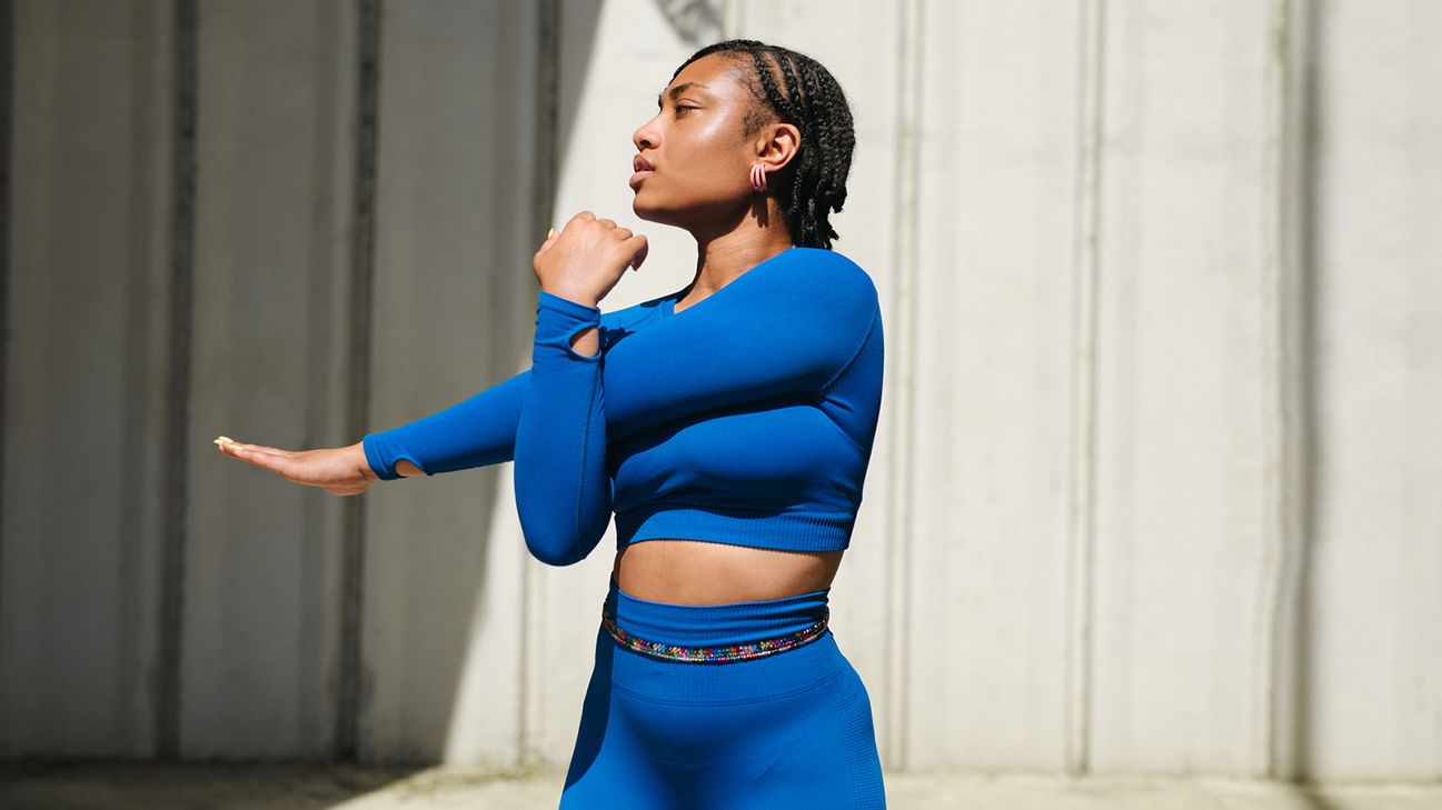 person stretching arms in blue workout clothes