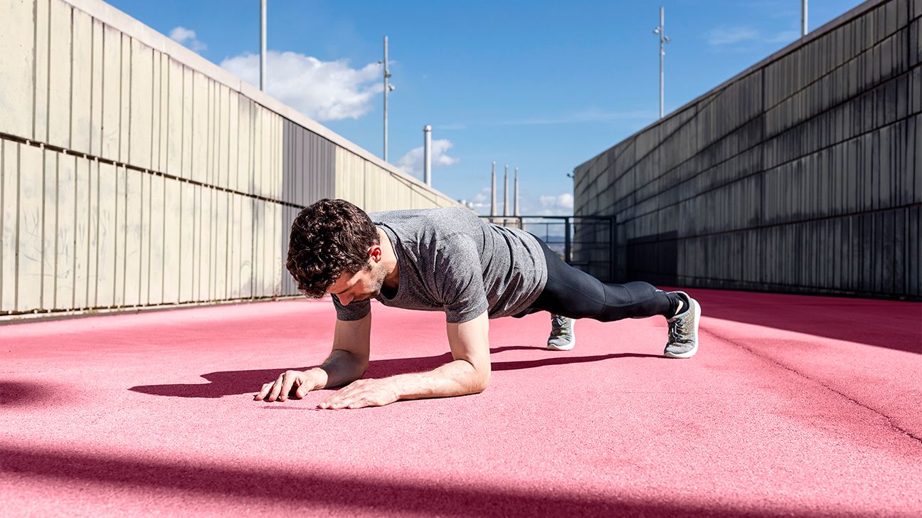 Sportive man exercising outdoors between walls exercising abs header crop